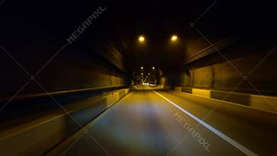 Low-key passage through an underground tunnel with an asphalt road. First-person view, filmed with an action camera