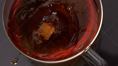 Sugar cube falling into cup of tea