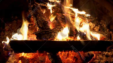 Fire burns in fireplace with logs glowing embers during cool evening gathering by friends in cozy