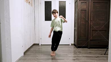 Caucasian boy doing an exercise jumping from side to side on one place in a home interior. Children workout. Funny child