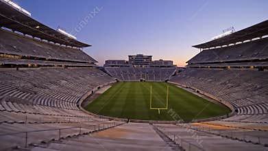 Football stadium at sunset with empty seating and goalposts overlooking the field