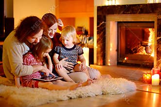 Happy family using a tablet pc by a fireplace