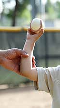 Adult Supporting Child Holding Baseball During Practice