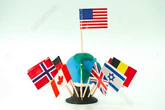 Flags of different countries surround a small globe made of clay during a school project showcasing global cultures in a classroom
