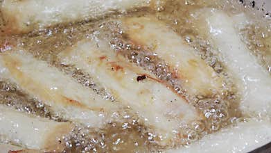 Spring rolls being deep-fried to a golden crisp.