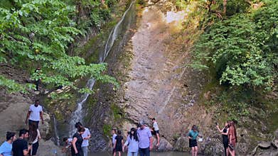 A group of tourists admires the Seven Beauties Waterfall, a picturesque natural complex of seven cascades of different heights