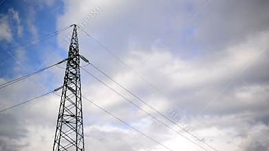 High voltage electric power pylon and lines with time lapse clouds in background.