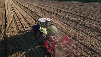 Tractor cultivating soil in agricultural field after harvest
