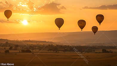 A group of hot air balloons are flying in the sky over a field