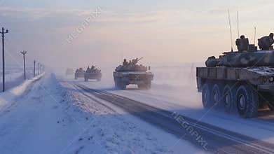 Military convoy drives through snowy landscape during winter at dawn in a remote area