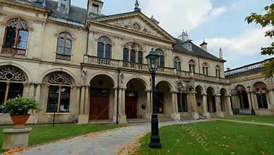 Elegant Waddesdon Manor facade with architectural details and green lawn under a cloudy sky