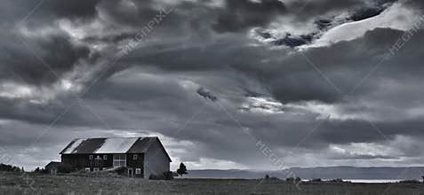 A black and white photo of a cloudy sky and an old building