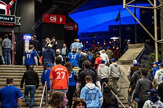 Blue Jays fans walking toward Rogers Centre before the baseball game at night.