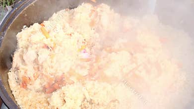 rice, meat and carrots are cooked in a cauldron