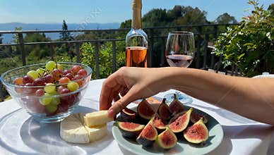 Outdoor picnic with rosÃ© wine cheese figs and grapes overlooking a scenic landscape view today