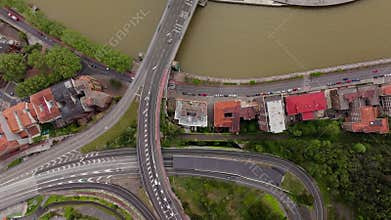 Top down aerial view of traffic on a highway interchange transitioning to La Salve Bridge over the Nervion river