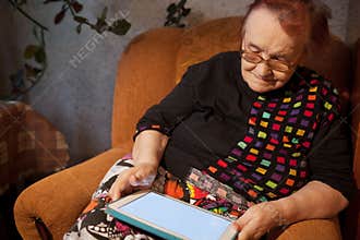 Elderly lady sitting in an chair using a tablet