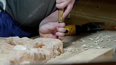 Closeup white woodworker refining relief edges with chisel, chips falling across bench, cordless drill idle behind