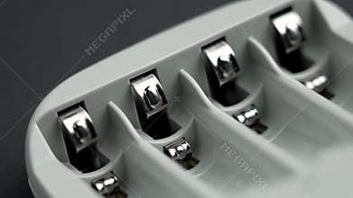 AAA batteries charger with exposed metallic terminals on black background.