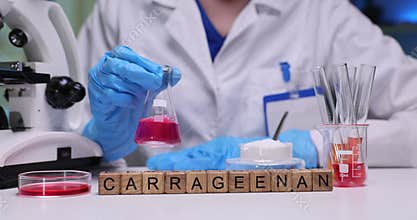 Laboratory worker rotates glass beaker filled with pink liquid