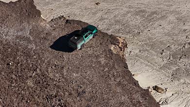 Aerial view of a pickup truck driving along a cliff edge of Bozjyra
