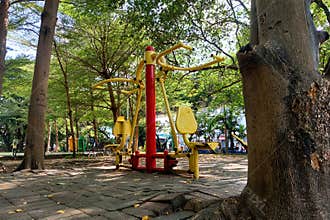 An outdoor fitness area featuring bright yellow and red exercise equipment