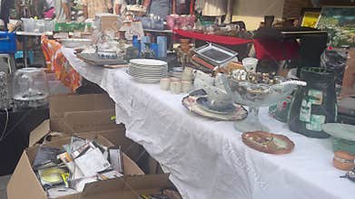Camera pans along tables of vintage items at Shuk Pishpishim flea market.