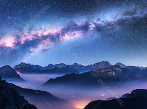 Milky Way above mountains in fog at night in autumn