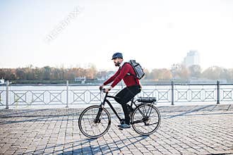 Hipster businessman commuter with electric bicycle traveling to work in city.