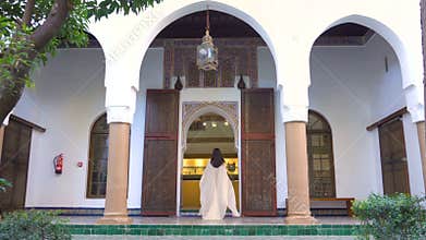 Beautiful Moroccan Girl Waving her white mantle in Picturesque Dar Si Said Riyad in Marrakech at sunset time