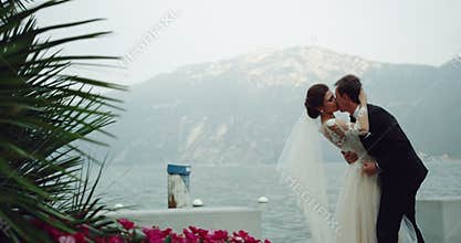 Amazing bride in white long dress kissing romantic with the groom in a beautiful place wonderful landscape in the