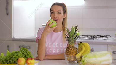 Healthy breakfast, happy smiling woman eating green fresh apple on kitchen