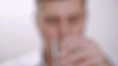 A man shows a tablet while holding it with his fingers, then swallows it and drinks it with water