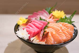 Mixed sliced fish sashimi on ice in black bowl. Sashimi Salmon Tuna Hamachi Prawn and Surf Calm set, raw fish, japanese food in