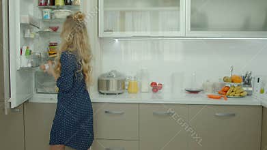 Casual woman taking food ingredients out of fridge