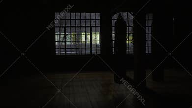 Panning shot from the inside of a boxing gym, filmed behind punching bags. Punching bag on the background of a window in