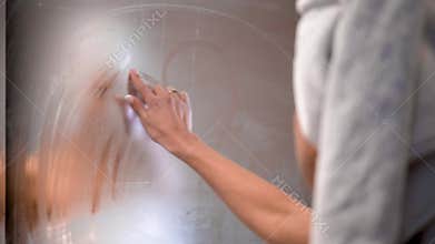 The girl draws a finger the heart on the bathroom mirror