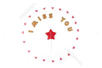Valentines day concept. Text I MISS YOU from cookies, frame made of paper hearts. In the center lollipop in form star. Flat lay