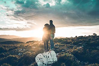 Happy couple hugging watching a sunset on the mountain. Romantic concept and love