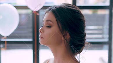 Attractive brunette with childish face and perfect healthy skin, alluring soft features, looks up, lowers her eyes