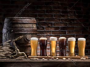Glasses of beer and ale barrel on the wooden table. Craft brewery