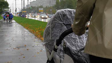 Mum walking with baby on rainy autumn day