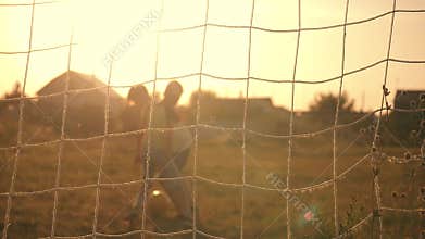 Two boys playing soccer at sunset. A soccer ball is hitting. Football goal. Children`s dreams of victories