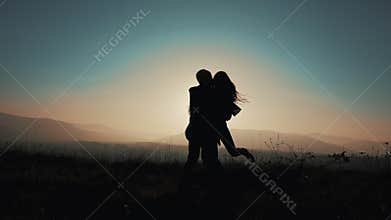 A loving couple runs to meet each other in embrace, man twists his woman against the sunset on the mountains. Slow