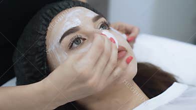 Close up face of beautiful girl does cosmetic procedure in beauty salon, slow motion