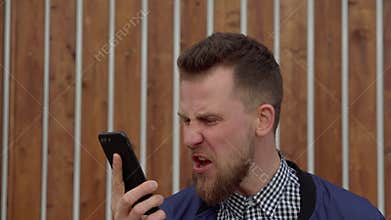 Furious man is shouting in cell phone, swearing with interlocutor, close-up