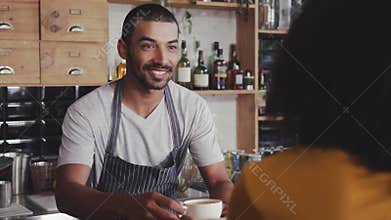 Barista offering coffee to the customer in cafe