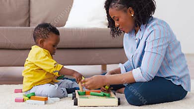Mother and baby playing with toy blocks at home