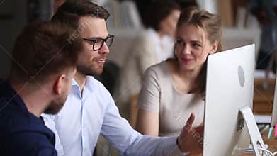 Three happy colleagues working together discussing computer project in teamwork