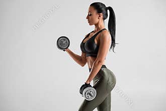 Fitness woman doing exercise for biceps on gray background. Muscular woman workout with dumbbells